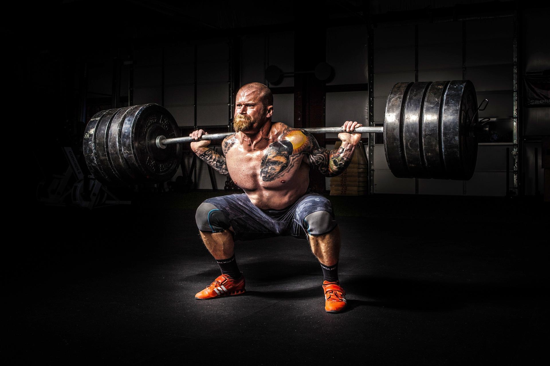 Puissance mécanique Image d'un homme qui soulève des poids dans une salle de sport StudySmarter