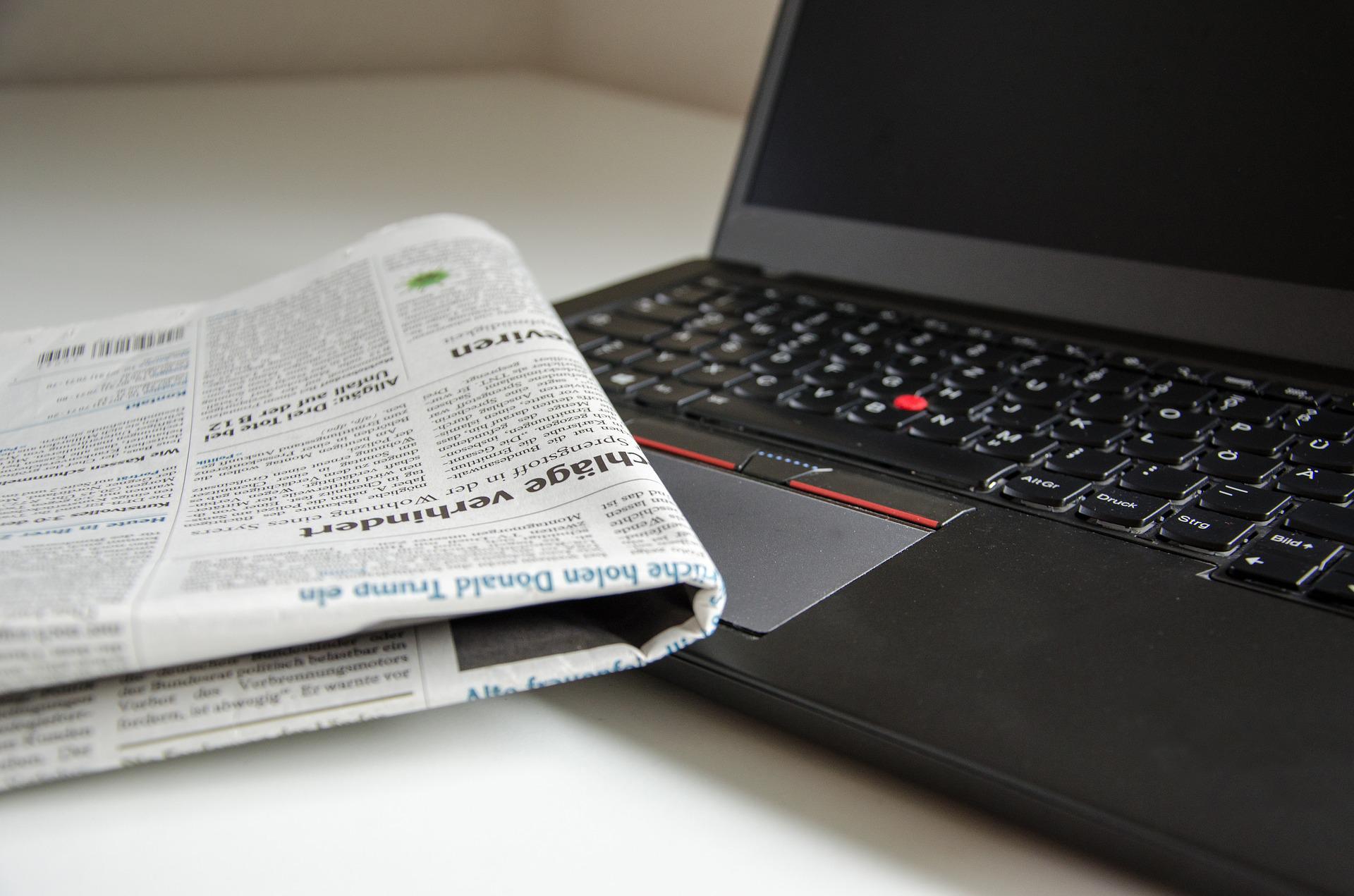 Inference. A newspaper half-covers a laptop. StudySmarter.