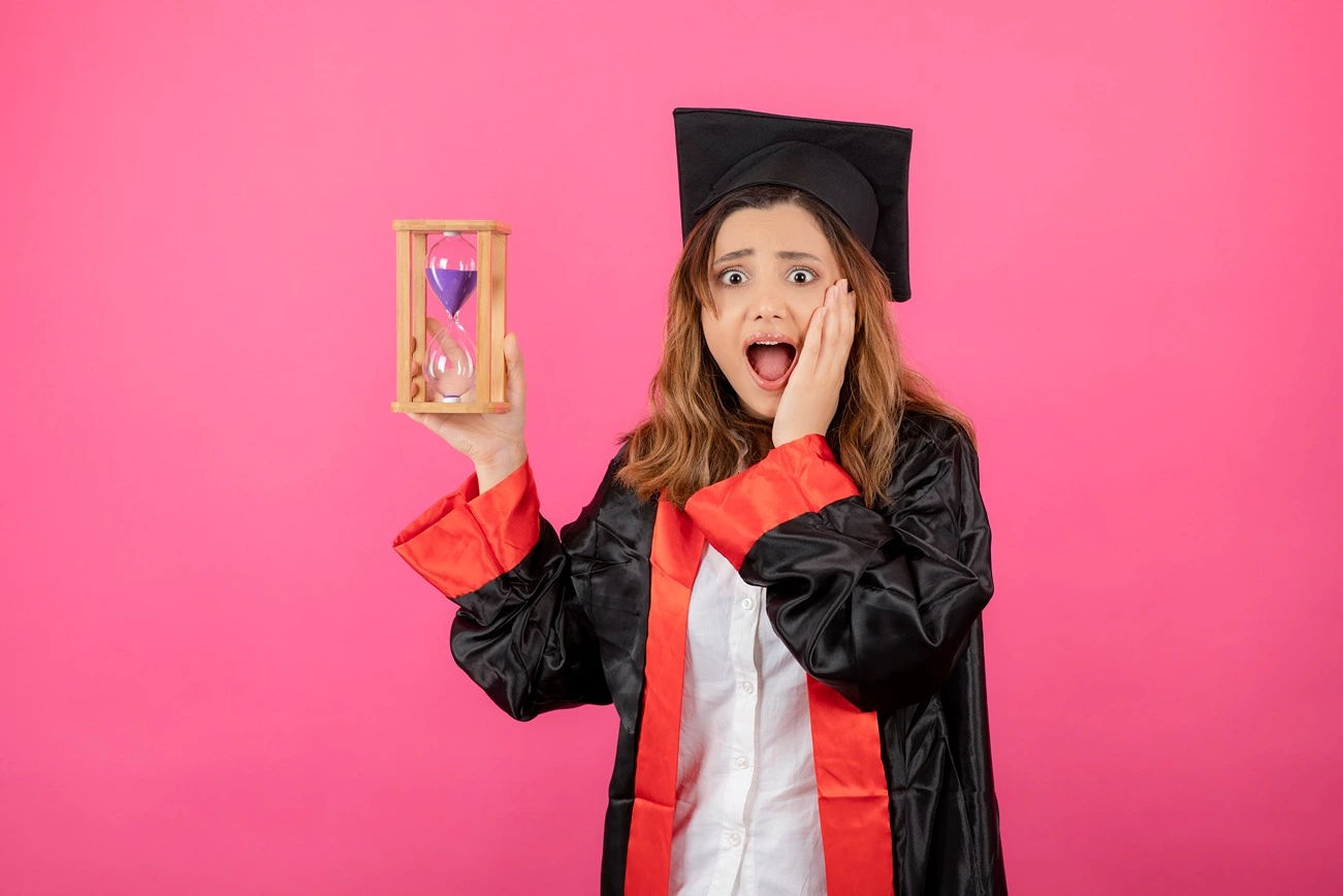 Social Development in Adulthood, a girl in graduate regalia holding an hour glass, StudySmarter