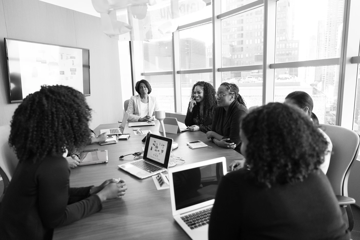 Feminist Theory of Education, Black and white image of women sitting in a conference room, StudySmarter