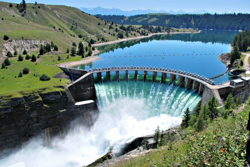 Sources d'énergie renouvelables Photographie d'un réservoir d'eau avec de l'eau tombant du réservoir à travers un barrage dans un canal StudySmarter