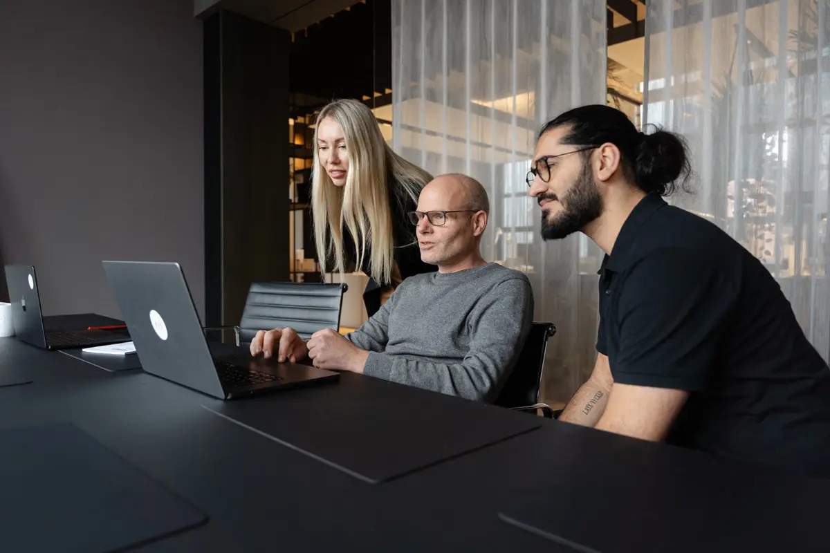 Image shows 3 colleagues at Tallence working together in front of a laptop