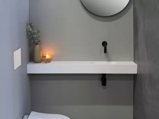 Strakke toiletruimte met fonteinset en ronde spiegel