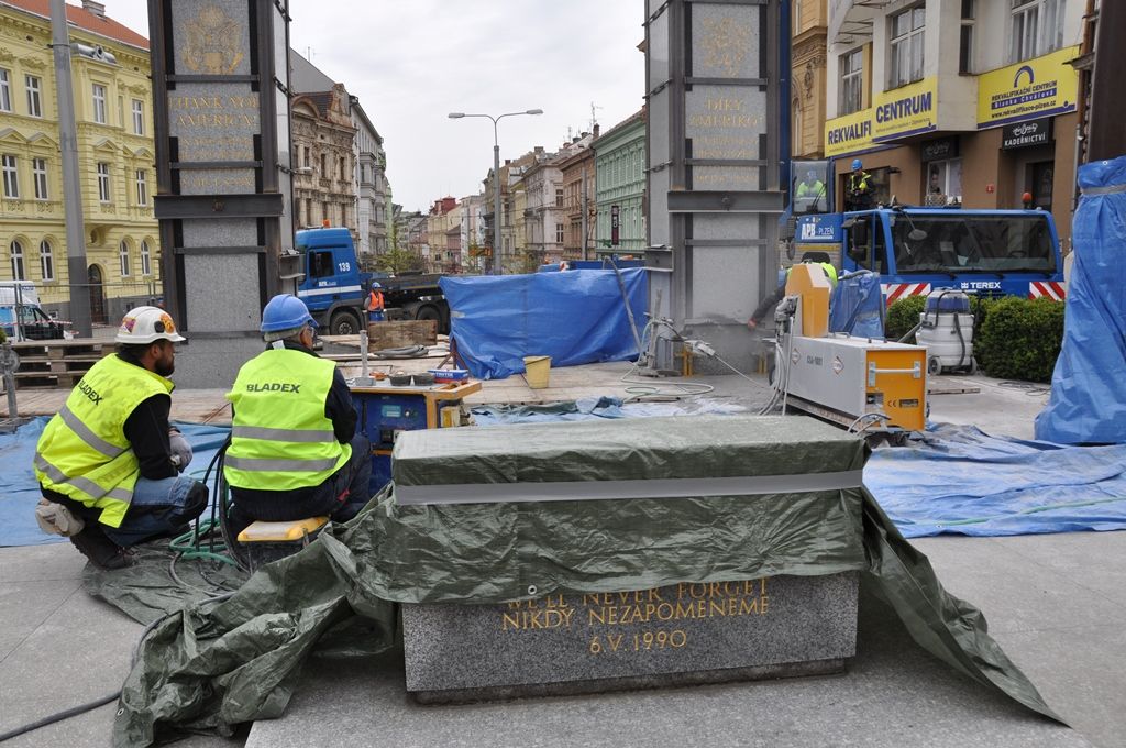 Zhruba deset hodin trvaly sobotní práce na odstranění dvou poškozených žulových pylonů pomníku Díky, Ameriko! v Plzni. Na technicky náročný zákrok se přišlo postupně podívat během dne několik stovek lidí. Specializovaná firma už v pátek zpevnila mnohatunové kvádry bandáží, aby je stáhla, dnes pak pomocí lanové pily oba dva odřízla ve výšce 38 centimetrů nad zemí. Na torzo obou pylonů byl kolem 19:00 nasazen tubus z nerezového plechu, který místo důstojně zakrývá a zůstane do doby, než budou zhotoveny pylony nové. (foto: 23.4.2016, E. Barborková)