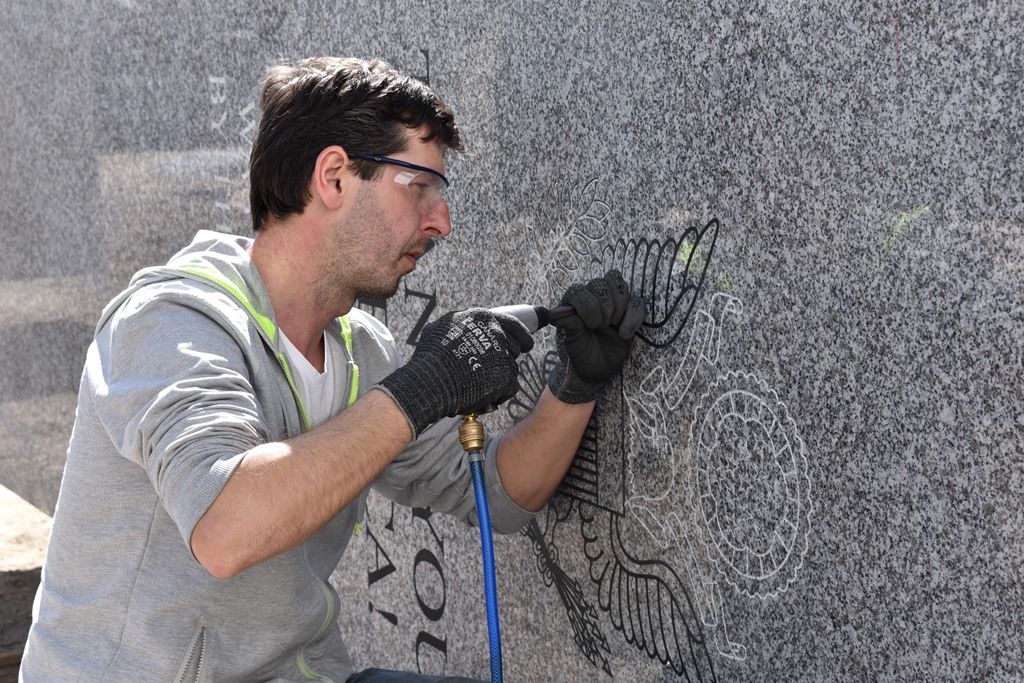 Zhotovení pylonů pro Díky, Ameriko! jde do finále, kamenosochař tesá nápisy