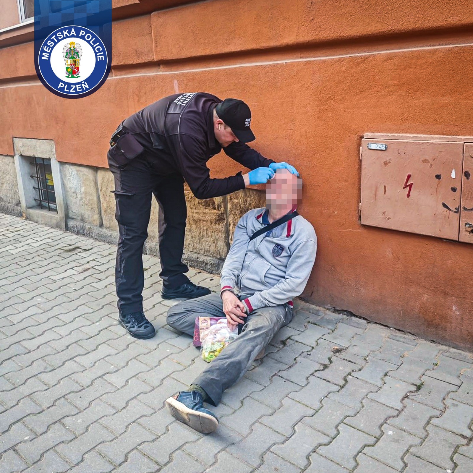 Pomoc zraněnému muži na chodníku