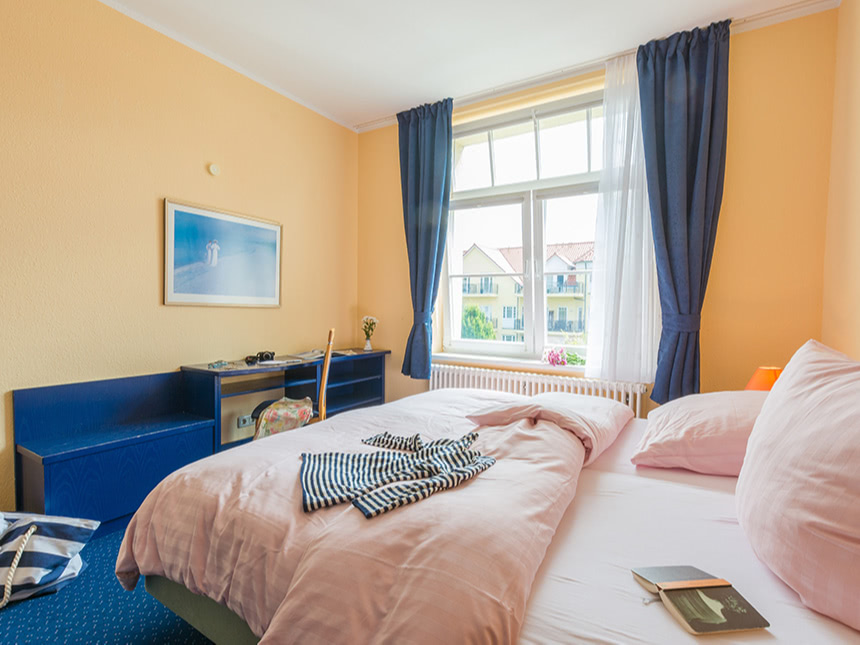 Doppelzimmer mit Doppelbett, Sitzbank und Ablage