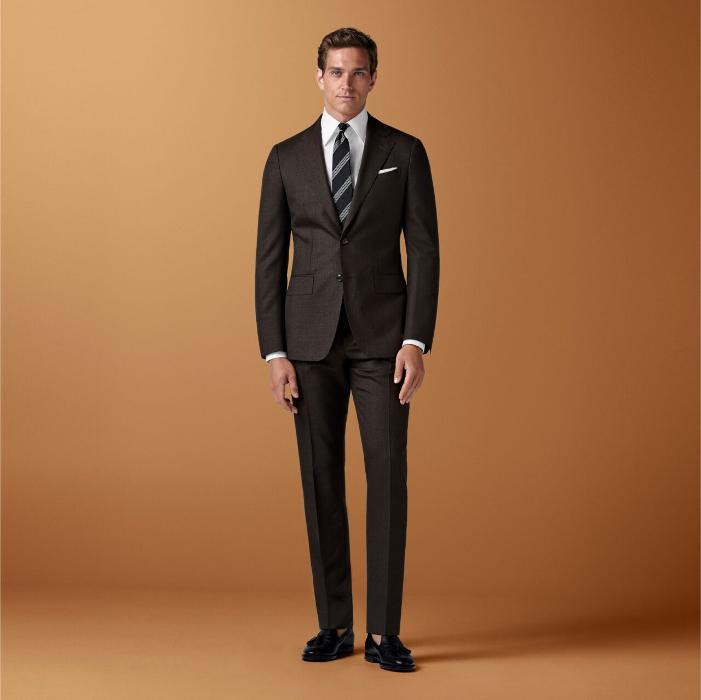 This dark brown suit features a tailored fit with a slim chest and waist, natural shoulders, and notch lapels. Paired with slim leg straight trousers, it includes a flat front and belt loops.