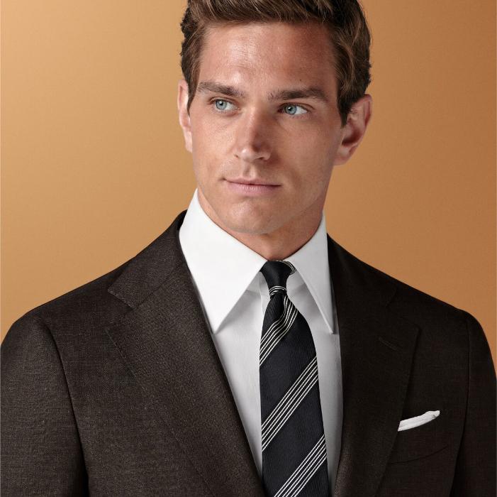 This dark brown suit features a tailored fit with a slim chest and waist, natural shoulders, and notch lapels. Paired with slim leg straight trousers, it includes a flat front and belt loops.