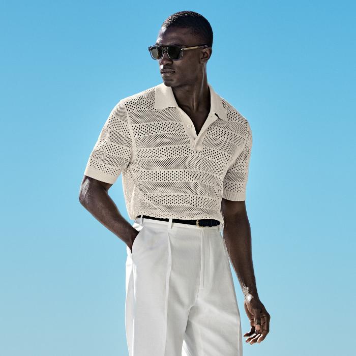 This sand button crochet polo is tailored to a slim fit and features a classic button collar, crochet texture, and ribbed hem and cuffs.