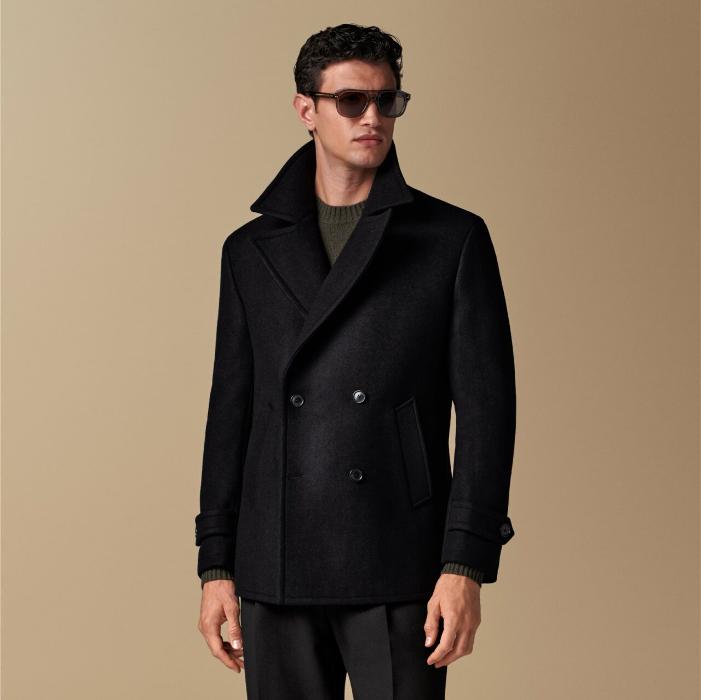 Timelessly elegant black peacoat with a double-breasted closure. Features lightly padded shoulders, welted pockets, storm tab, and single vent. Tailored for comfort with inside pockets.