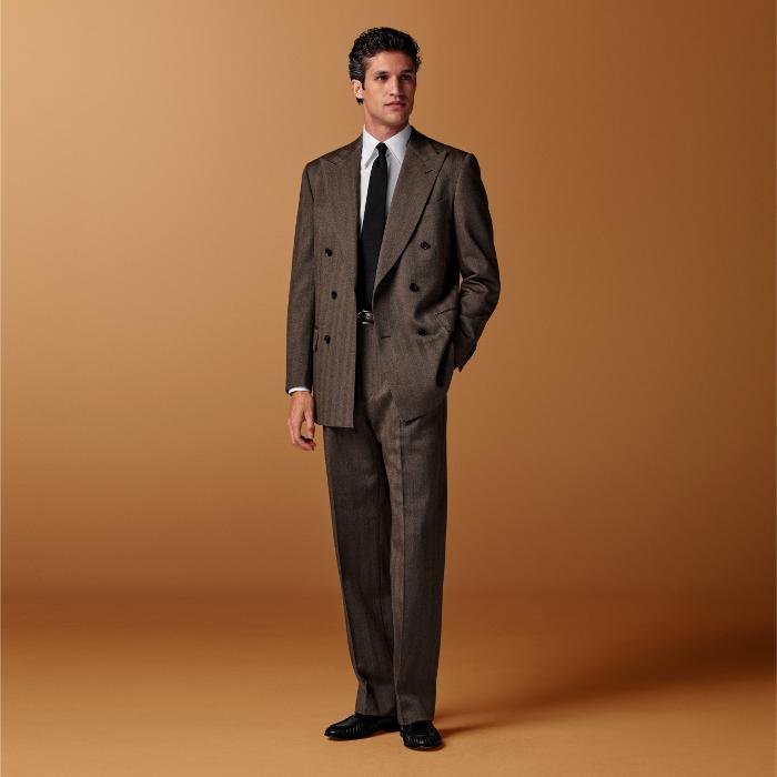 This mid brown herringbone suit is cut to a tailored fit with a padded shoulder and fitted silhouette. Paired with wide-leg straight trousers featuring a single pleat and belt loops.