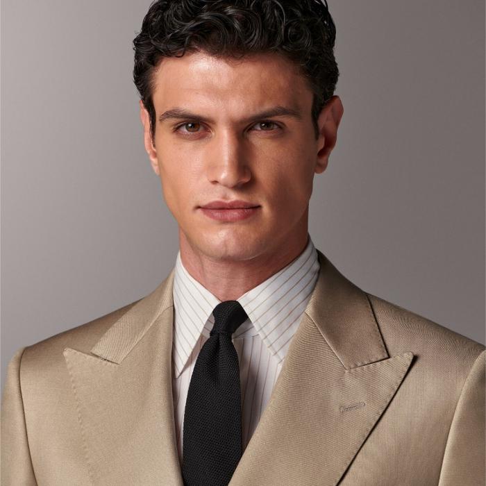 This sand suit is cut to a tailored fit with a padded shoulder and double-breasted closure for a sleek look. Paired with straight-leg trousers featuring a flat front and belt loops for a refined finish.