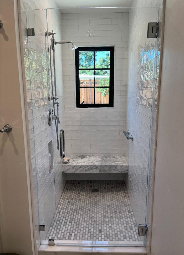 This bathroom remodel features a shower with stone mosaic tile, blending vintage character with modern shower design and a neutral palette that creates timeless tranquility.