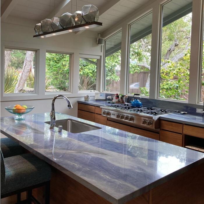 Azul Macaubus quartzite countertops bring a striking natural surface to this light-filled kitchen, paired with horizontal-grain walnut cabinetry and a professional-grade stove for modern function and timeless design.