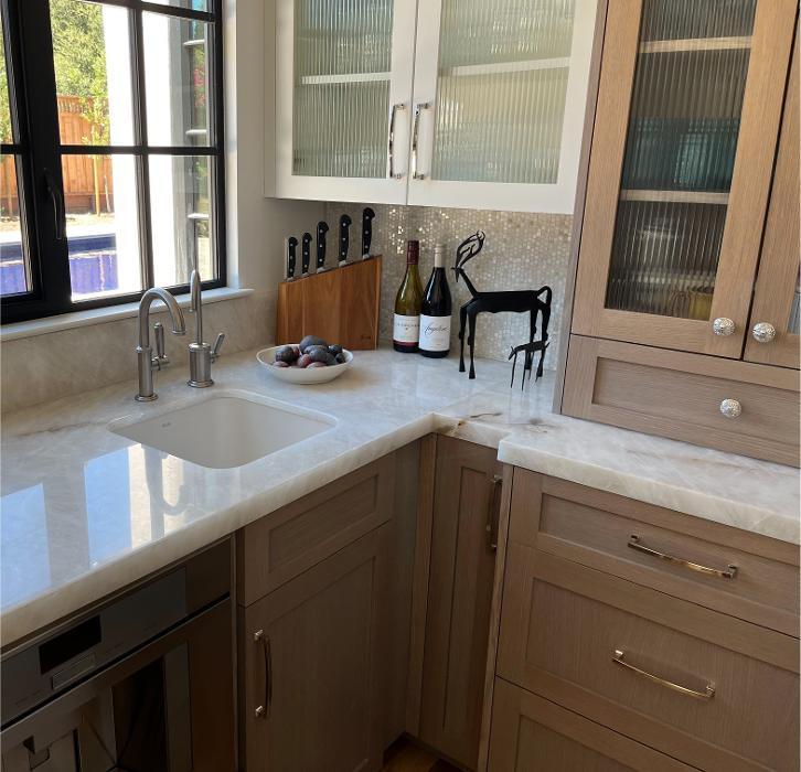 The butlers pantry is defined by Bianco quartzite countertops, a split joint marble mosaic backsplash, and custom cabinetry in a mix of crisp white and warm wood tonesan elegant balance of function and modern detailing.