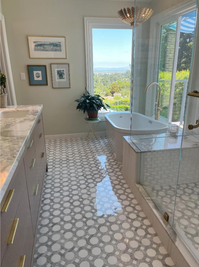 This refined bathroom design features octagonal mosaic flooring, Dolomite marble shower walls, and a graceful freestanding tub. Decorative lighting enhances the space, uniting function and artistry in a modern bathroom remodel.