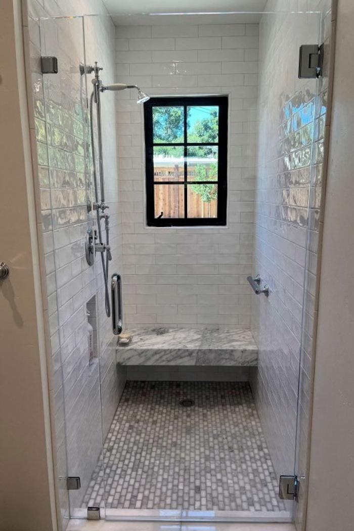 This bathroom remodel features a shower with stone mosaic tile, blending vintage character with modern shower design and a neutral palette that creates timeless tranquility.