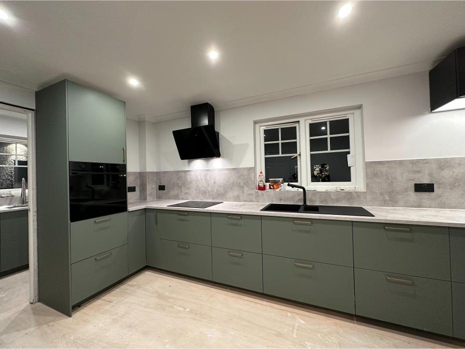 Contemporary Glasgow kitchen renovation by PJTC Ltd featuring sage green units, integrated appliances, induction hob, black extractor, under-mount sink, and concreteeffect worktops.