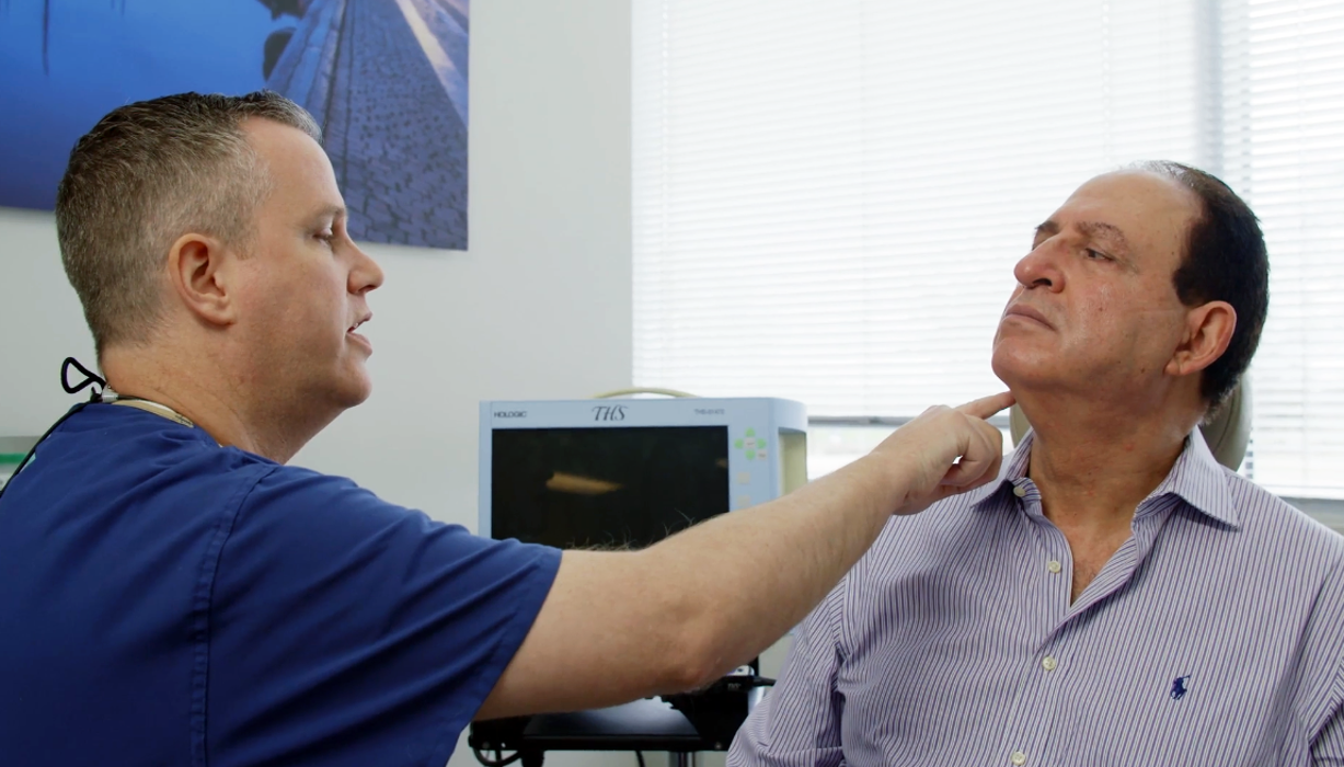Richard Thrasher, MD, checking patient's neck and thyroid gland