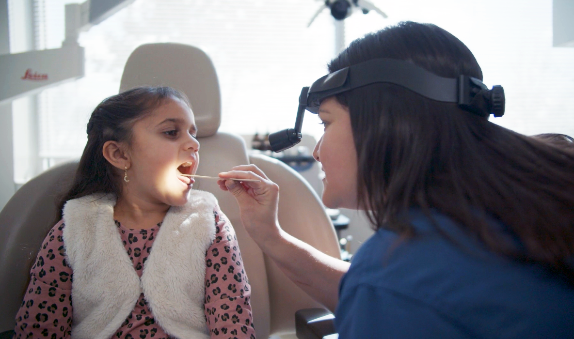 Sakeena Payne, MD, checking a pediatric patient's mouth and throat