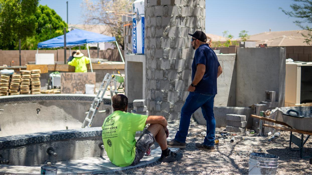AE Outdoor Living construction team reviewing progress on a custom pool and outdoor living build. Hands-on project management and on-site quality control.