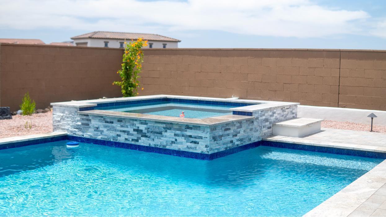 Modern pool and raised spa with stacked-stone veneer. Clean tile lines and a smooth water finish showing AE Outdoor Living&rsquo;s custom pool design quality.