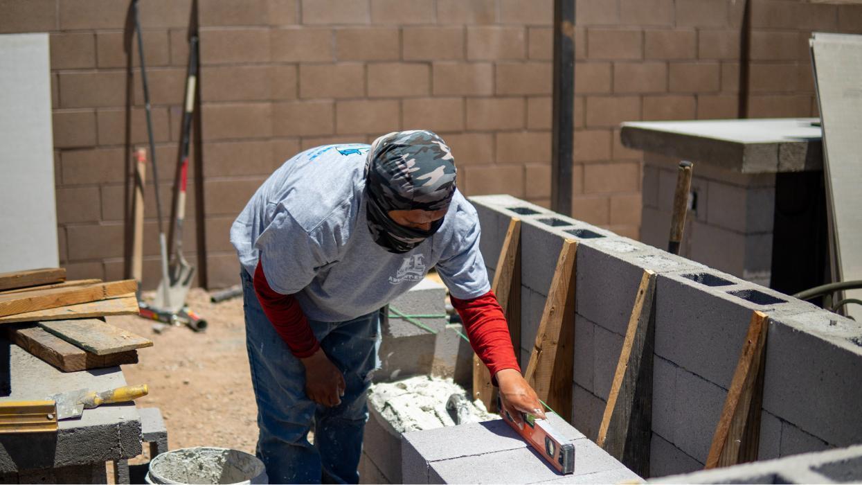 On-site progress of pool and outdoor living features. AE Outdoor Living team managing masonry, plumbing, and structure work.