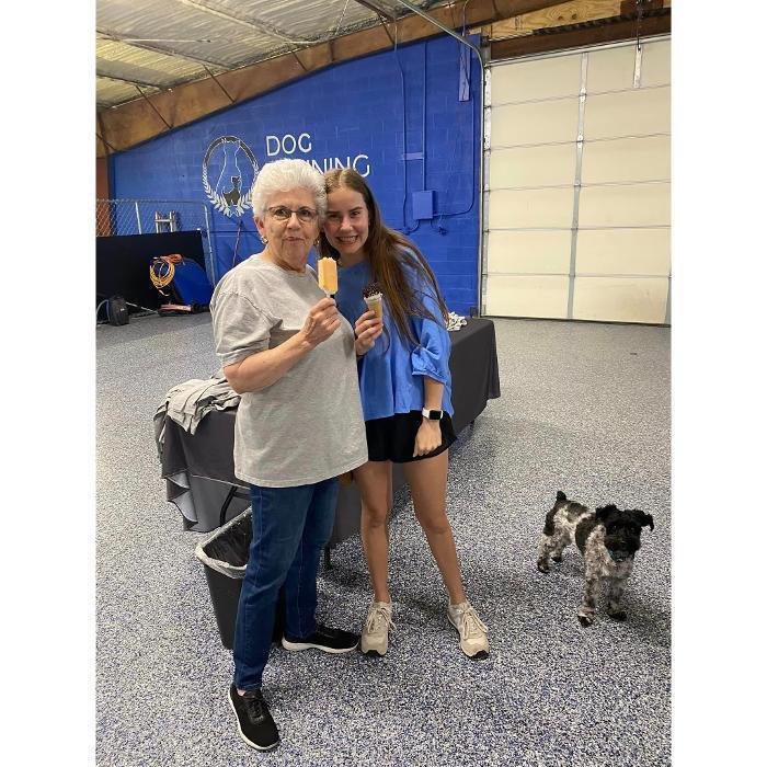 A smiling couple standing outside a building with their small dog on a leash.