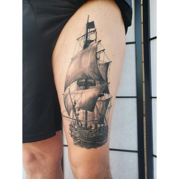 Black and gray realism ship tattoo by Cory. Detailed sailing vessel on thigh with smooth shading and fine detail.