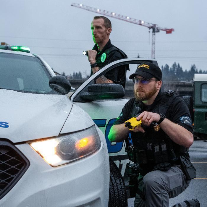 Two security officers training to respond to an alarm activation while using appropriate force to detain a suspect