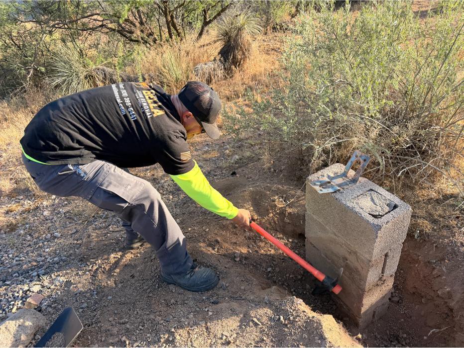 Digging up a concrete block pier using a pickaxe.