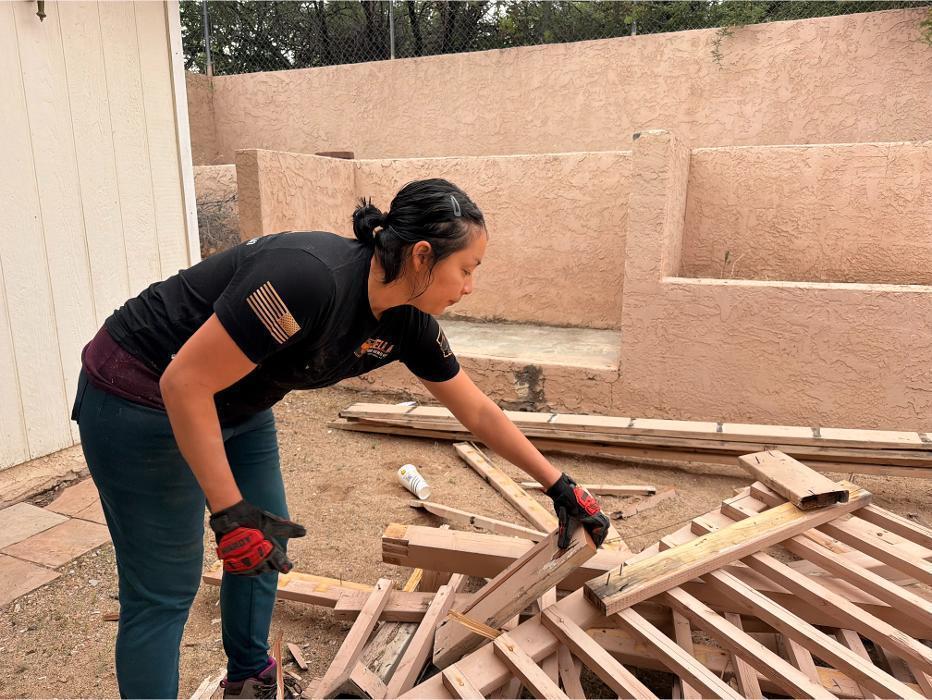 Victoria picking up lumber from a deck demolition.