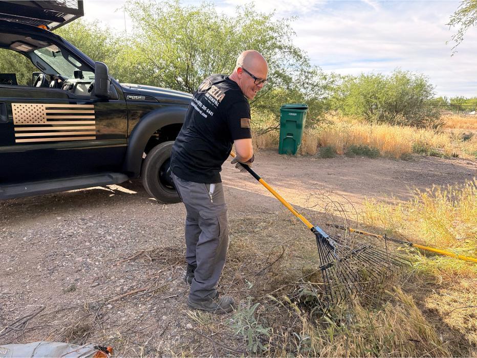 Bella Junk Removal crew member raking yard debris during a yard cleanup job.