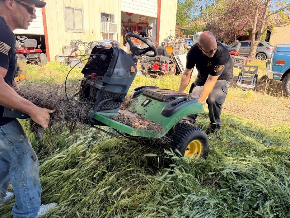 Robert and Joe positioning a riding mower at the ramp before winching it into the truck.