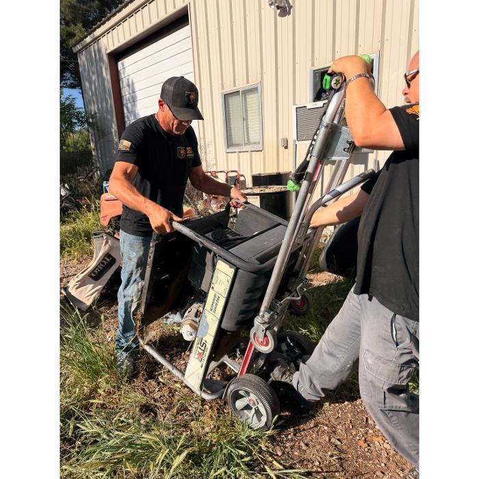 Robert and Joe loading a generator onto a hand truck for removal in our F-550.