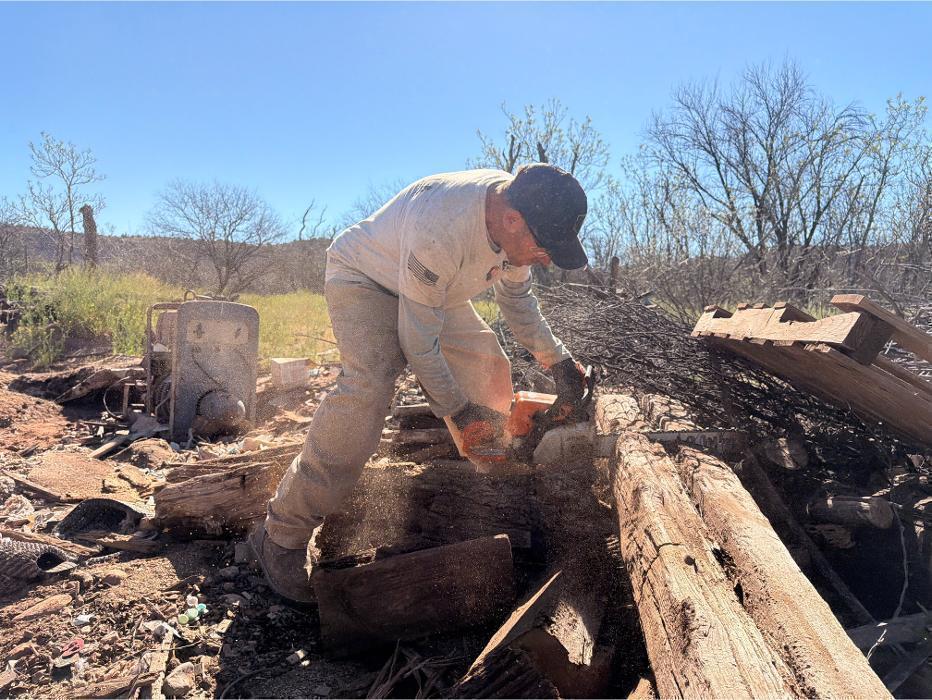 Joe cutting lumber down to size with a chainsaw for loading and removal.