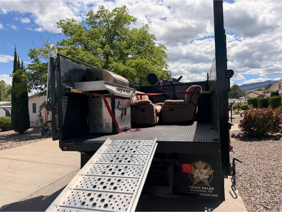 Bella Junk Removal dump truck loaded with junk with the loading ramp set up on site.