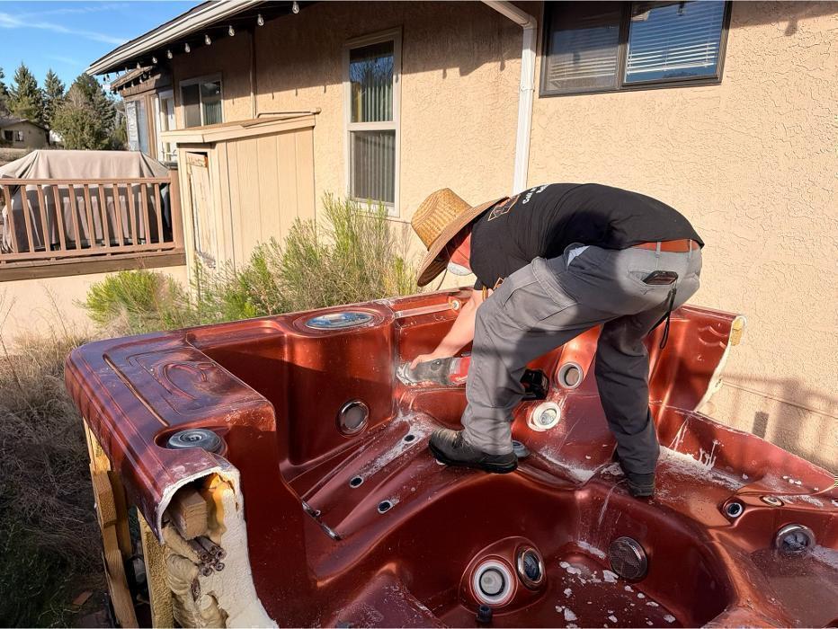 Robert cutting apart a hot tub with a reciprocating saw for removal.