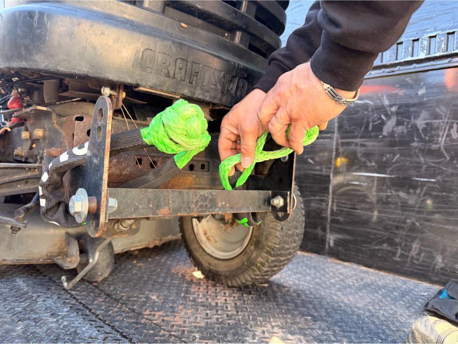 Robert removing soft shackles from a riding mower after winching it into the F-550 dump truck.