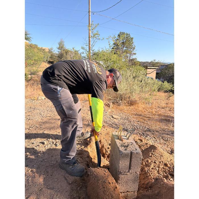Digging up a concrete block pier using a shovel.