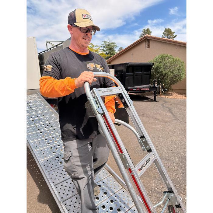 Bella Junk Removal crew member wheeling a hand truck down the dump truck ramp during a junk removal job.