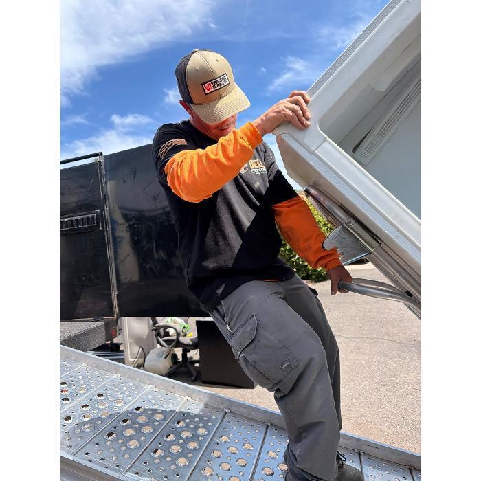 Bella Junk Removal crew member loading a refrigerator up the ramp into the dump truck.