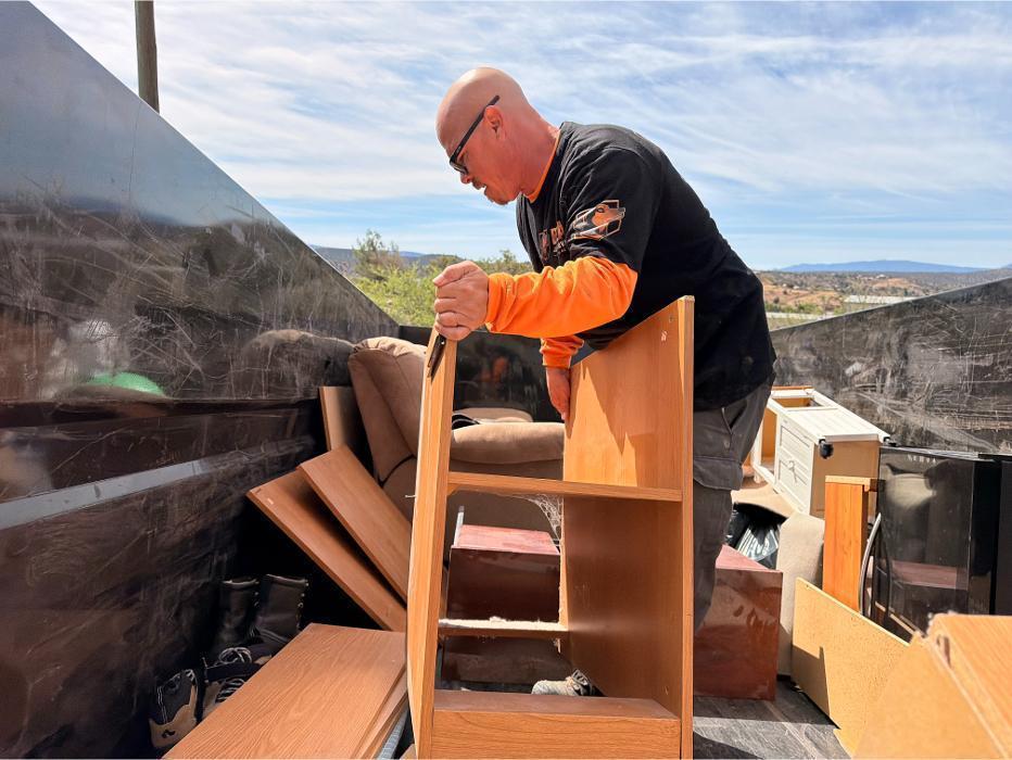 Bella Junk Removal crew member loading broken furniture into the dump trailer during a junk removal job.