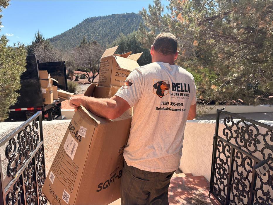 Joe carrying a stack of cardboard boxes to the truck during a cleanout job.
