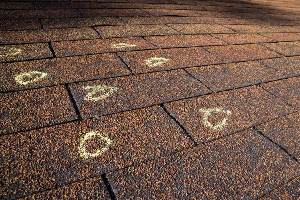 Asphalt shingle roof with hail damage outlined in chalk.