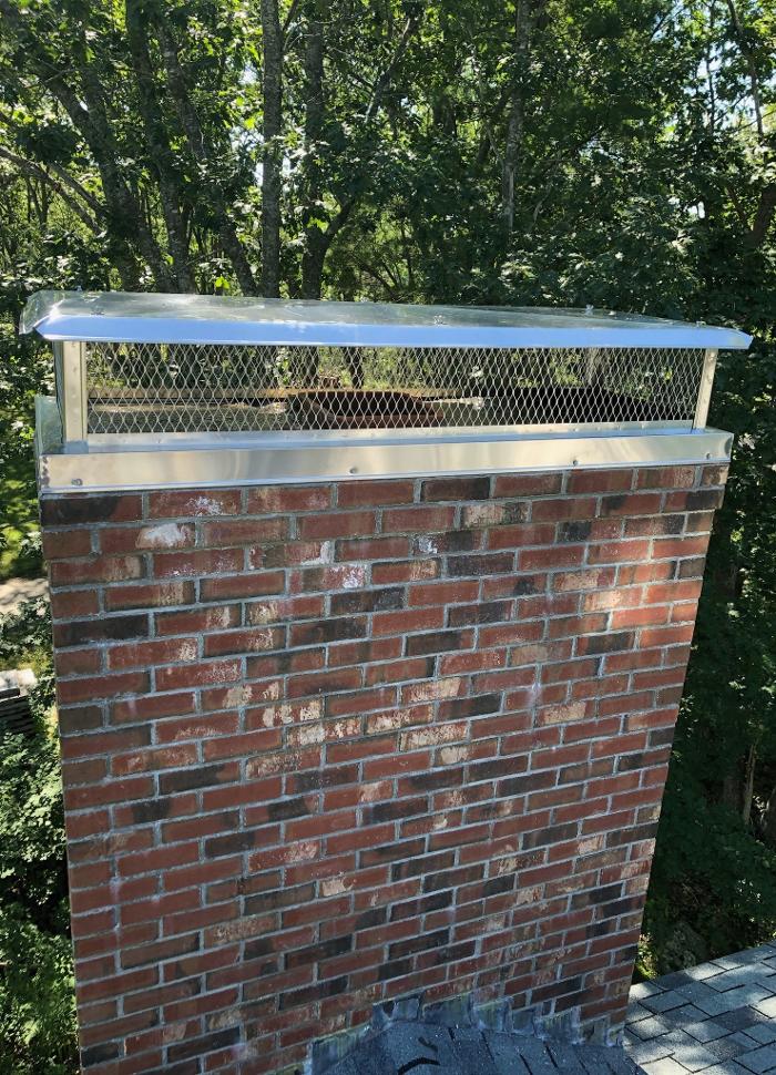 Stainless steel custom chimney cap installed on a brick chimney in Portsmouth, ME to improve draft and protect against moisture.