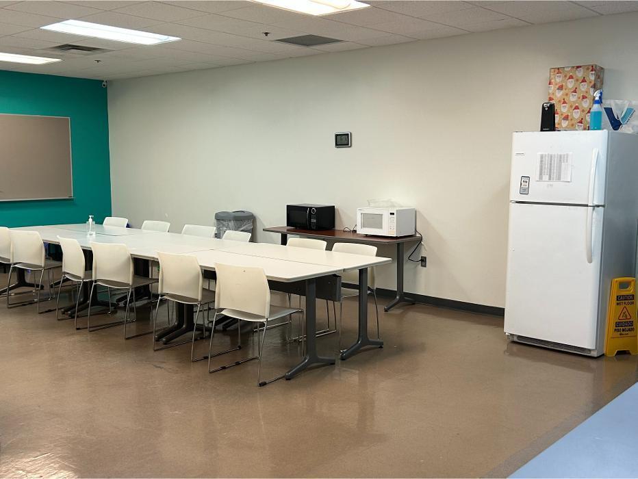 A professional staff breakroom or meeting area with long white tables, multiple chairs, a refrigerator, and microwaves for the Camen Behavioral team.