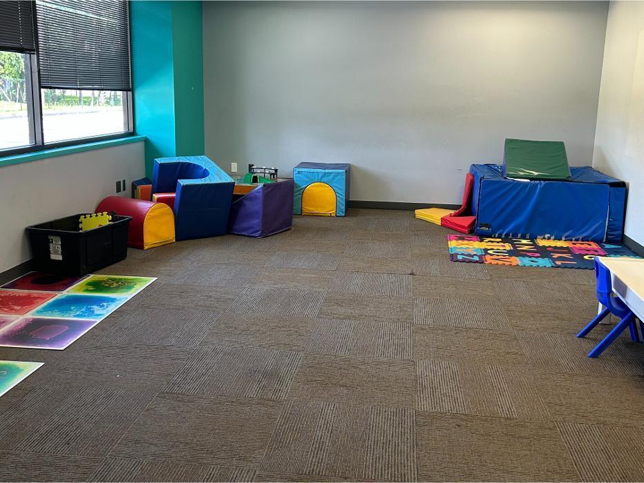 Padded play therapy area designed for autism and behavioral therapy sessions with foam climbing blocks and sensory activity stations.