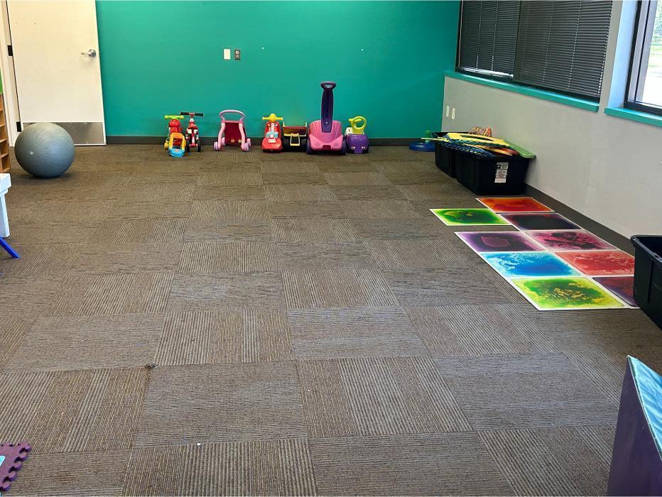 Clinic-based ABA therapy room at Camen Behavioral Services featuring sensory play equipment, ride-on toys, and open space for child behavioral therapy sessions.
